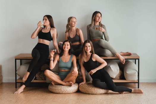 A group of young athletic girls are in the fitness room after a workout. Women resting after yoga classes.