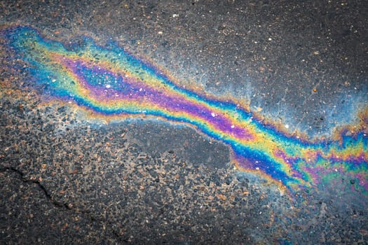 Water with patches of gasoline and oil. Spilled oil on the asphalt road background.