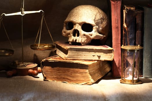 Nice vintage still life with human skull near balance and books