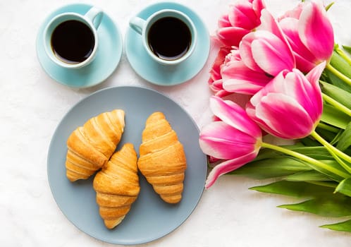 two cups of coffee, croissants and a bouquet of pink tulips, beautiful morning.