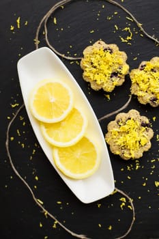 lemon cupcakes on a black background with lemon peel, close-up