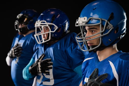 Portrait of three men in blue uniforms for American football with a hand on his chest on a black background