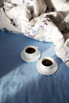 two cups of coffee in bed, sunlight.