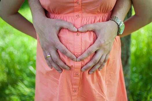 A Pregnant Belly with fingers Heart symbol.