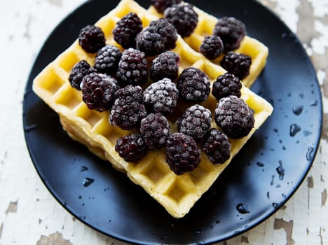 Belgian waffles with blackberry on an old wooden table.