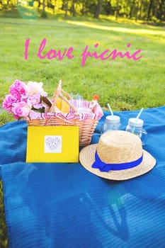 Beautiful flowers in a basket and a yellow album lie on the grass-inscription I love picnic