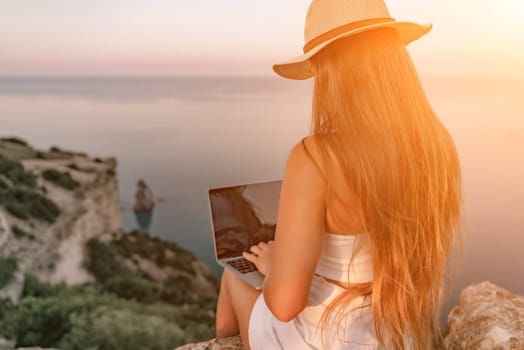 Freelance women sea working on the computer. Good looking middle aged woman typing on a laptop keyboard outdoors with a beautiful sea view. The concept of remote work