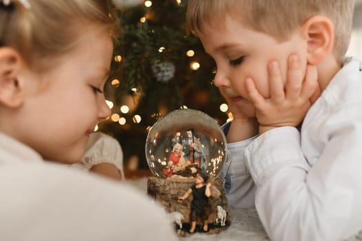 The kids and christmas glass ball with a nativity scene