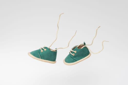 Two green baby shoes flying in the air simulating walking on a white background. Levitation concept