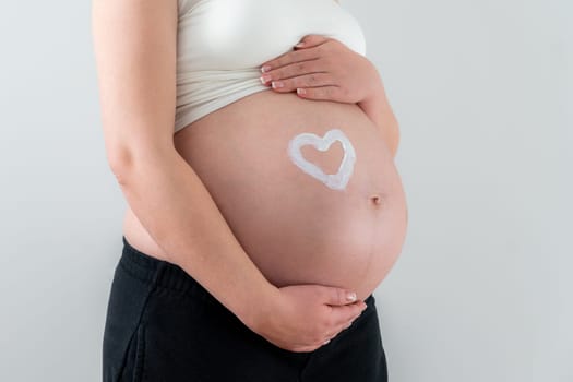 White drawing of a heart shape on pregnant woman belly