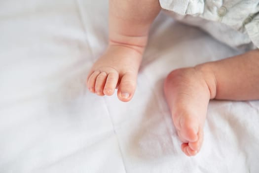 Small feet of a newborn baby on the bed, top view. The concept of motherhood, breastfeeding