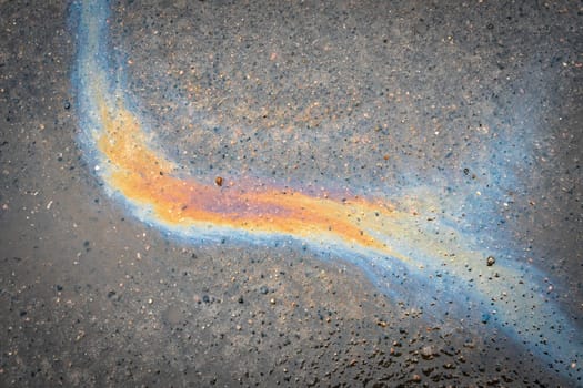 Rainbow gasoline oil spill on the pavement as a texture or background.