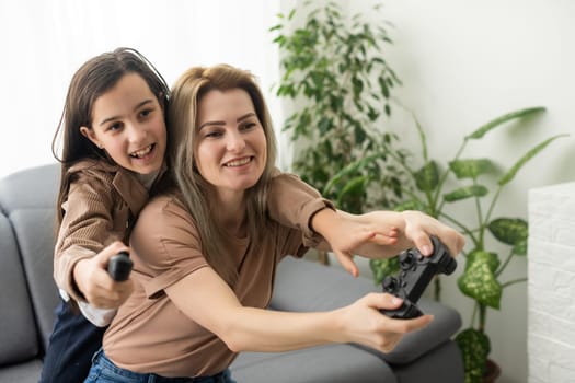Photo of domestic funny blond lady mom daughter sitting comfy couch hold joystick playing video games stay home safety quarantine spend weekend together best friends living room indoors