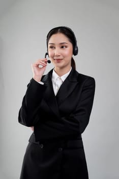 Attractive asian female call center operator with happy smile face advertises job opportunity on empty space, wearing a formal suit and headset on customizable isolated background. Enthusiastic