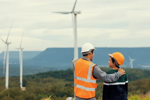 Engineer with his son on a wind farm atop a hill or mountain in the rural. Progressive ideal for the future production of renewable, sustainable energy. Energy generation from wind turbine.