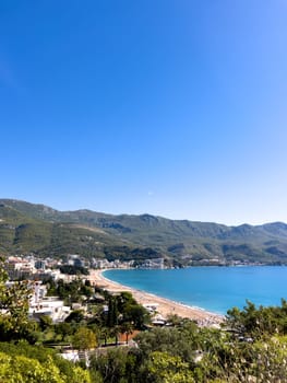 Hotels among green trees on the seashore at the foot of the mountains. High quality photo