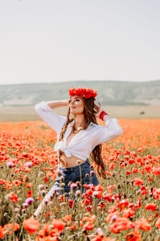 Happy woman in a poppy field in a white shirt and denim skirt with a wreath of poppies on her head posing and enjoying the poppy field