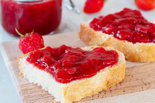 Wheat bread toasts with spread strawberry jam on the table.