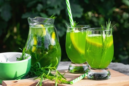 Homemade summer refreshing tarragon lemon drink on patio table.