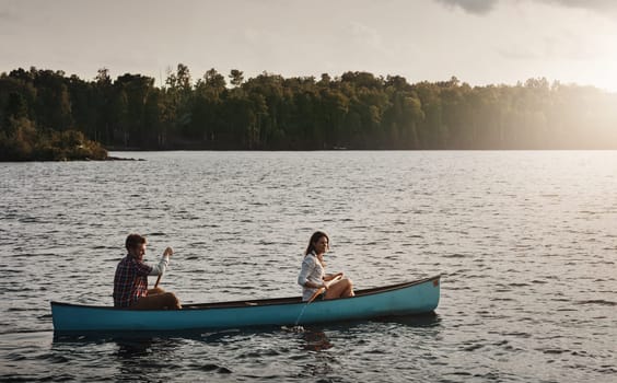 Enjoying the beauty in nature. a young couple rowing a boat out on the lake