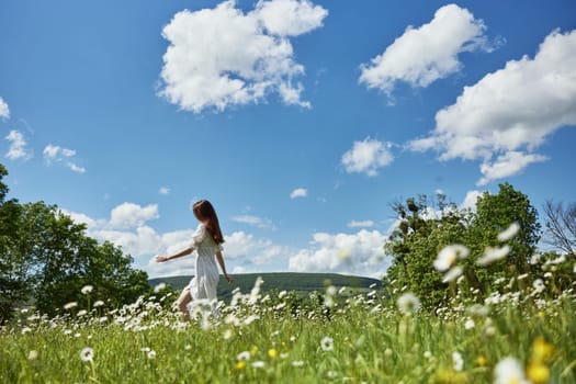 a woman in a light dress runs far across a chamomile field against a blue sky, enjoying harmony with nature. High quality photo