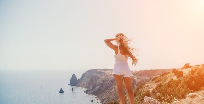 Woman travel sea. Young Happy woman in a long red dress posing on a beach near the sea on background of volcanic rocks, like in Iceland, sharing travel adventure journey