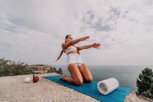 Woman sea pilates. Sporty, middle-aged woman practicing pilates in park near the sea. trains on a yoga mat and exudes a happy and active demeanor, promoting the idea of a healthy lifestyle through exercise and meditation.