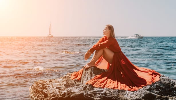 Woman travel sea. Young Happy woman in a long red dress posing on a beach near the sea on background of volcanic rocks, like in Iceland, sharing travel adventure journey