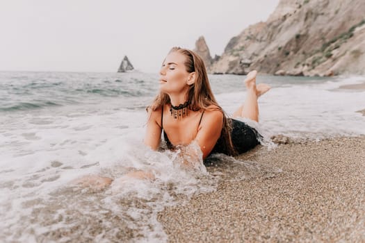 Woman travel sea. Young Happy woman in a long red dress posing on a beach near the sea on background of volcanic rocks, like in Iceland, sharing travel adventure journey