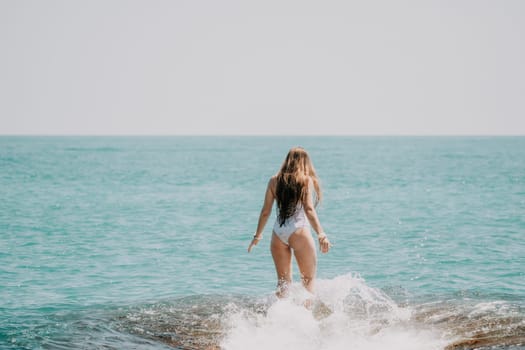 Woman sea yoga. Back view of free calm happy satisfied woman with long hair standing on top rock with yoga position against of sky by the sea. Healthy lifestyle outdoors in nature, fitness concept.