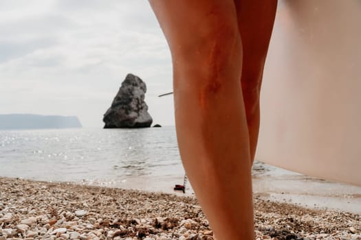 Close up shot of beautiful young caucasian woman with black hair and freckles looking at camera and smiling. Cute woman portrait in a pink bikini posing on a volcanic rock high above the sea