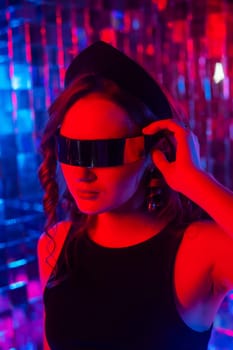 Close-up portrait of a caucasian woman in sunglasses in neon light against a mirror wall