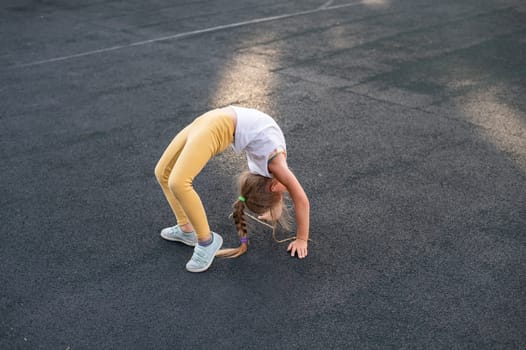 Caucasian girl doing bridge exercise on sports ground outdoors