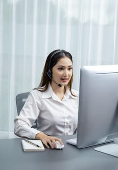 Asian call center with headset and microphone working on her laptop. Female operator provide exceptional customer service. Supportive call center agent helping customer on inquiry. Enthusiastic