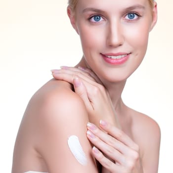 Closeup personable beautiful woman putting skincare moisturizer cream on her arm looking in camera in isolated background as concept for beauty care treatment. Female model applying lotion on her body