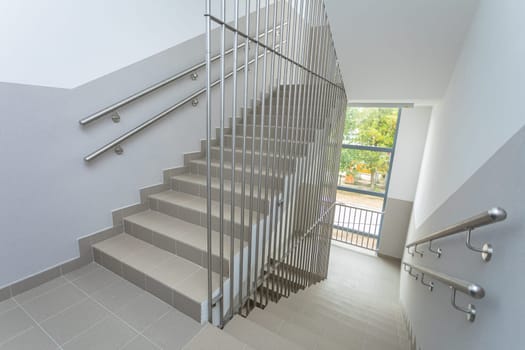 A view of the spacious and airy staircase with stainless steel bar protection made. Tube handrails mounted to the wall.