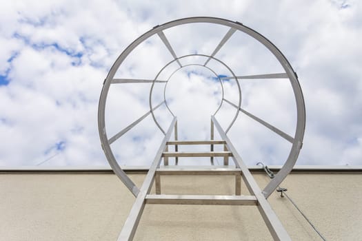 Bottom view of the stainless steel ladder mounted on the building facade. Technical access on the outside of the building to the higher part of the roof.