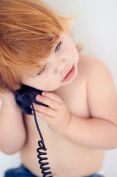 Phone call, playing and cute young kid at home with ginger hair and youth. Conversation, telephone and learning child with communication and listening in a house with confidence and childhood.