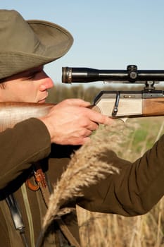 Hunting, gun and man on a Africa safari in field for shooting animals on wildlife holiday. Weapon, sniper and male person aim for wild game in nature with hunt and scope for target shot in the sun.