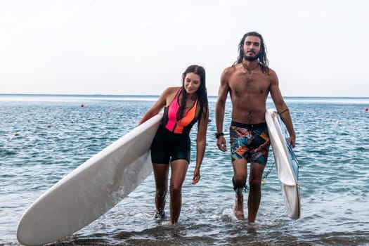 Sea woman and man on sup. Silhouette of happy young woman and man, surfing on SUP board, confident paddling through water surface. Idyllic sunset. Active lifestyle at sea or river