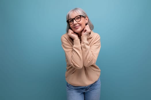 a middle-aged woman in a youth outfit flaunts on a studio background with copy space.