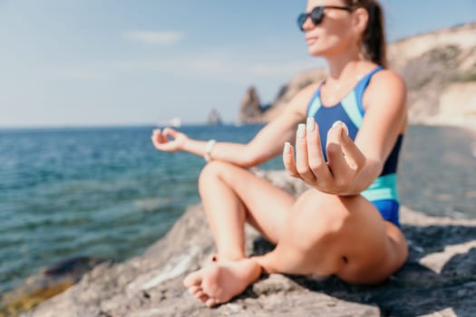 Woman sea yoga. Back view of free calm happy satisfied woman with long hair standing on top rock with yoga position against of sky by the sea. Healthy lifestyle outdoors in nature, fitness concept.