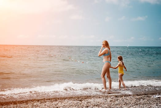 Happy loving family mother and daughter having fun together on the beach. Mum playing with her kid in holiday vacation next to the ocean - Family lifestyle and love concept.