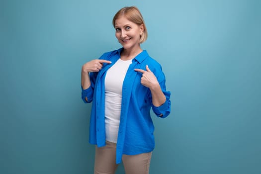 mature woman shows her hands in different directions on a blue background with copyspace.