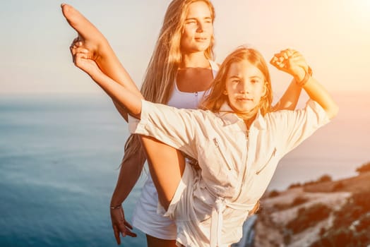 Close up portrait of mom and her teenage daughter hugging and smiling together over sunset sea view. Beautiful woman relaxing with her child.