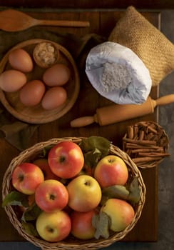 Top view on a ripe apples on a wooden table in basket with ingredients for pie near