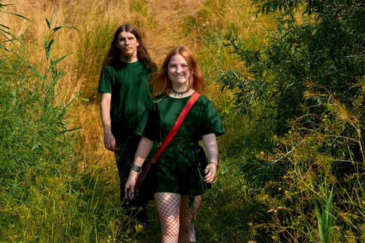 two individuals of the same sort considered together. Young cheerful couple guy and girl in green clothes are walking in the forest. High quality photo