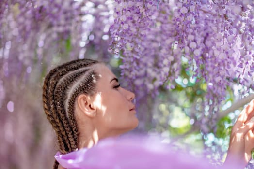 Woman wisteria lilac dress. Thoughtful happy mature woman in purple dress surrounded by chinese wisteria.