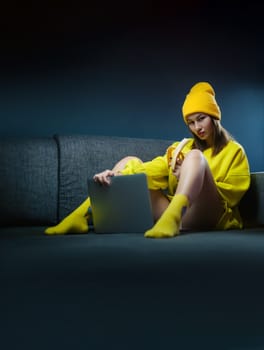 sexy girl in yellow clothes and a hat with a banana and a laptop on dark background copy paste