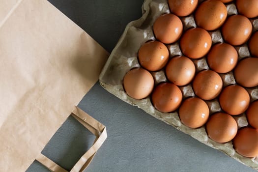 Chicken eggs lie in a tray on the kitchen surface with a paper bag. Buying products and goods in the store